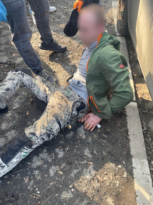 Zatrzymany mężczyzna leżący na ziemi po zatrzymaniu przez nieumundurowanych policjantów