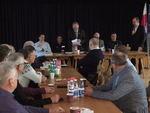 mezczyzni siedzacy przy stole obok policjantka w mundurze