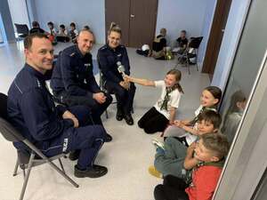 Trójka policjantów siedząca przed grupka dzieci