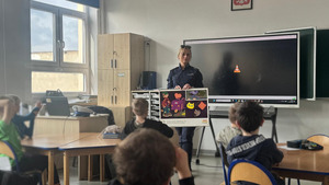 policjantka prezentuje tablicę edukacyjną i opowiada o noszeniu odblasków