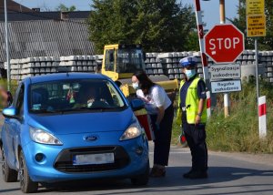 policjantka i przedstawicielka Polskich Linii Kolejowych przy samochodzie osobowym, który zatrzymał się przed szlabanem