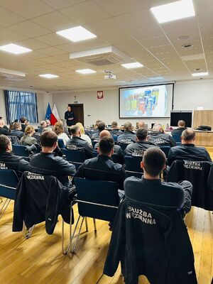 Policjant wraz z uczestnikami szkolenia.