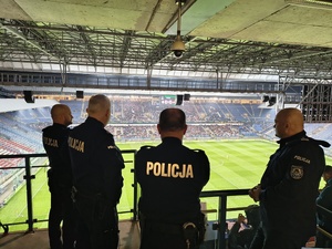 umundurowani policjanci obserwujący zachowanie kibiców na trybunach stadionu