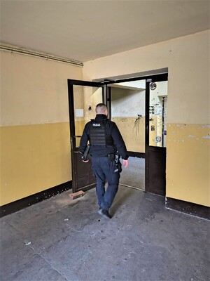 Dzielnicowy podczas wchodzenia do mieszkań socjalnych z wizytą.