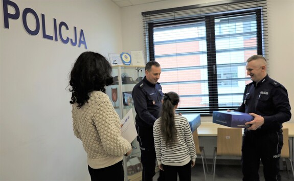 Komendant Wilk i Komendant Machniak wręczają upominki za wzorową reakcję 9-latce i jej matce