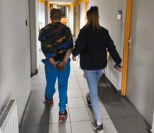 policjantka prowadzaca zatrzymanego mezczyzne