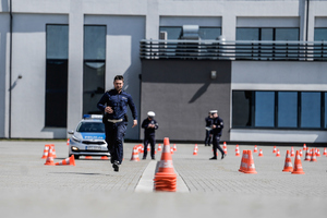 Policjant biegnący na placu pomiędzy pachołkami