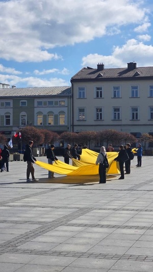 uczestnicy marszu trzymajacy żółta flage