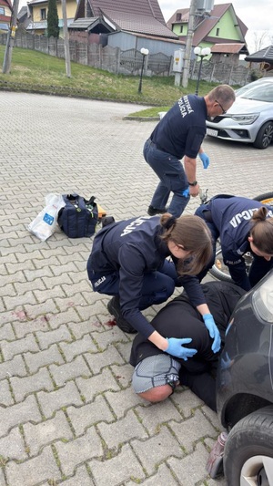 policjantka badajaca poszkodowanego lezacego na boku