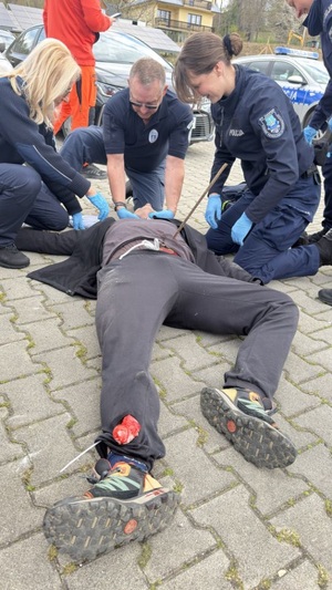 poszkodowany mezczyzna z wbitym pretem w brzuch lezacy na plecach obok funckjonariusze ze Słowacji i z Polski