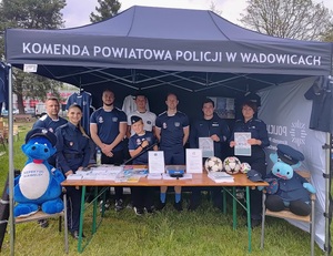 W namiocie czterech mężczyzn i chłopiec w sportowych strojach, policjant i dwie policjantki. Na stoliku gadżety