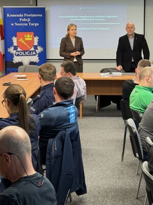Kobieta i mężczyzna obok emblematy komendy