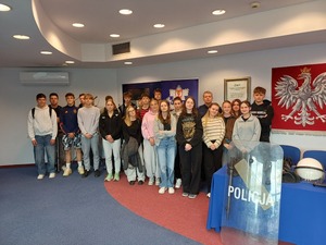 Licealiści stoją na auli komendy policji, obok na stole leży wyposażenie policjanta do służby