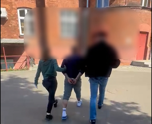 policjanci prowadzą do komendy zatrzymanego oszusta