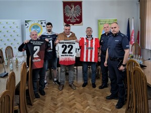 przedstawiciele klubów trzymający koszulki i policjanci