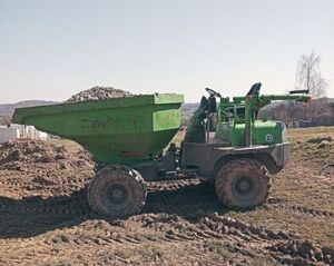 zielona maszyna budowlana - wozidło na gumowanych kołach wypałniona gruzem i ziemią