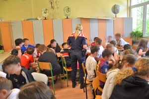 Umundurowana policjantka oraz uczniowie podczas spotkania profilaktycznego