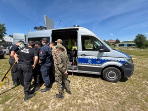 Obok policyjnego samochodu uczniowie klas mundurowych