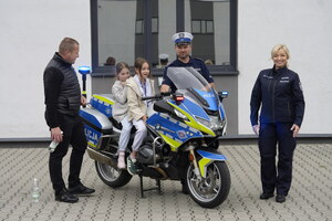 Policyjny motor, na którym siedzą dzieci, obok stoją policjanci oraz mężczyzna
