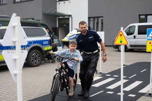 Policjant RD oraz dziecko na rowerze w trakcie pokonywania toru do nauki jazdy