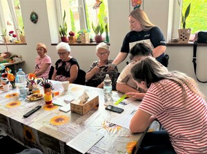 dzielnicowa rozdająca opaski odblaskowe podczas spotkania z seniorami