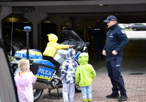 dzieci przy motocyklu, na którym siedzi jedno z nich, obok policjant prewencji
