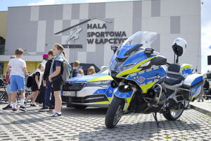 Policyjne pojazdy służbowe na tle hali sportowej w Łapczycy