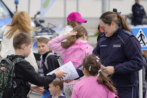 Policjantka rozdaje dzieciom materiały promocyjne