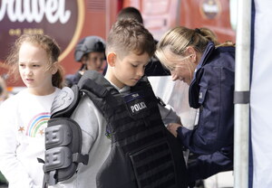 Policjanta pomagająca ubrać dziecku kamizelkę przeciwuderzeniową