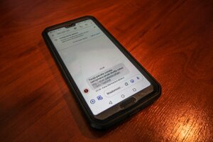 telefon komórkowy który wyświetla smsa z treścią "twoja paczka została zatrzymana przez służbę celną"