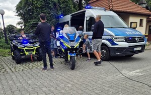 dzieci oglądają policyjny radiowóz i quad podczas pikniku