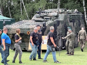 wojskowy pojazd, obok stoją żołnierze, a także przechodzacy uczestnicy pikniku