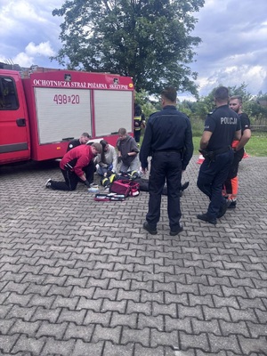 samochód straży pożarnej dwóch policjantow oraz czwórka młodziezy