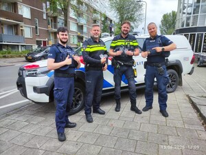 Policjanci polscy oraz holenderscy na tle radiowozu wraz z naszywkami
