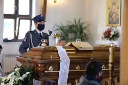 Policjant z kompanii honorowej stojący w kościele przy trumnie zmarłego kapelana