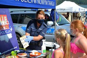 Policjantka rozmawia z dziećmi przy policyjnym stoisku