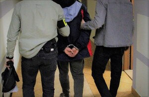 Policjanci pionu kryminalnego prowadzą zatrzymanego mężczyznę 1