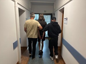 Policjanci i zatrzymany mężczyzna idący korytarzem