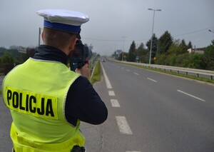 Policjant ruchu drogowego mierzy prędkość ręcznym miernikiem prędkości