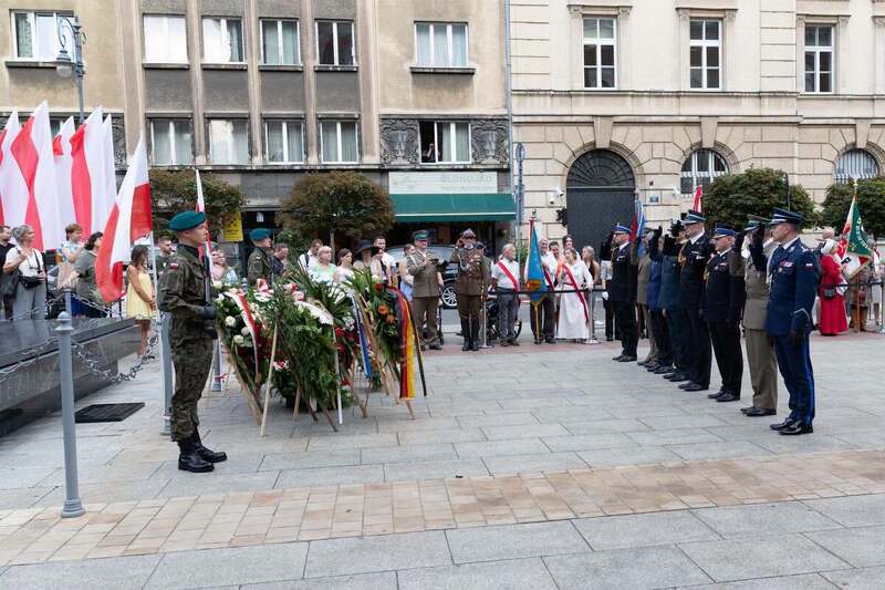 przedstawiciele służb mundurowych składają wieniec przed grobem nieznanego żołnierza.