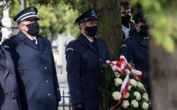 Policjanci składają wieniec na grobie.