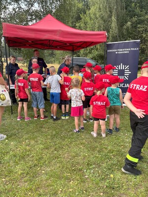 dzieci podchodzą do stanowiska policjantów w strażackich koszulkach