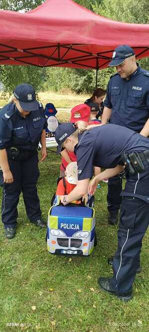policjanci pomagają chłopcu wejść do zabawkowego radiowozu
