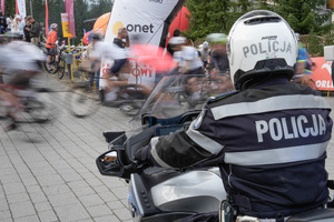 policjant na motorze przed nim jadą kolarze