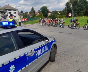 Zabezpieczenie Tour de Pologne V etap radiowoz i policjant przy ulicy w tle kolarze 2