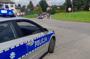 Zabezpieczenie Tour de Pologne V etap radiowoz i policjant przy ulicy w tle kolarze