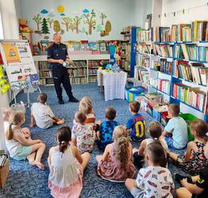 policjant z dziećmi w bibliotece podczas wspólnego czytania