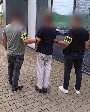 policjanci bez mundurów prowadzą zatrzymanego mężczyznę