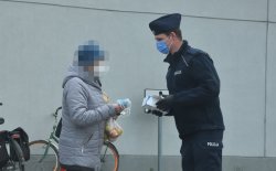 policjant z KP Gdów przekazuje maseczki kobiecie
