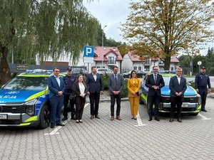Policjanci oaz samorządowscy przy radiowozach policyjnych.